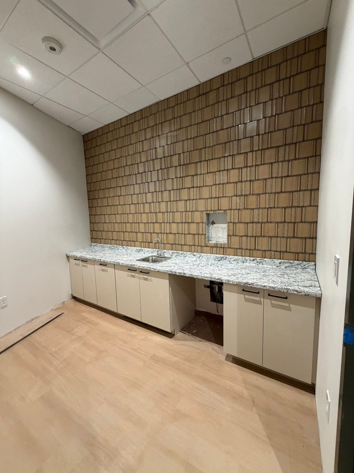 Break room feature wall in textured glazed tile above a granite counter