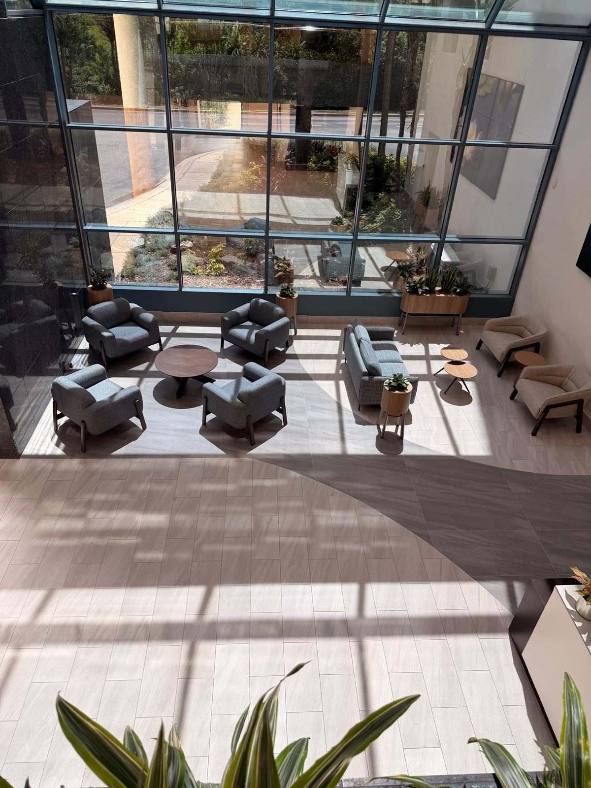Sand Lake IV lobby after completion — two-tone large-format porcelain floor with a curved inlay, seen from the mezzanine