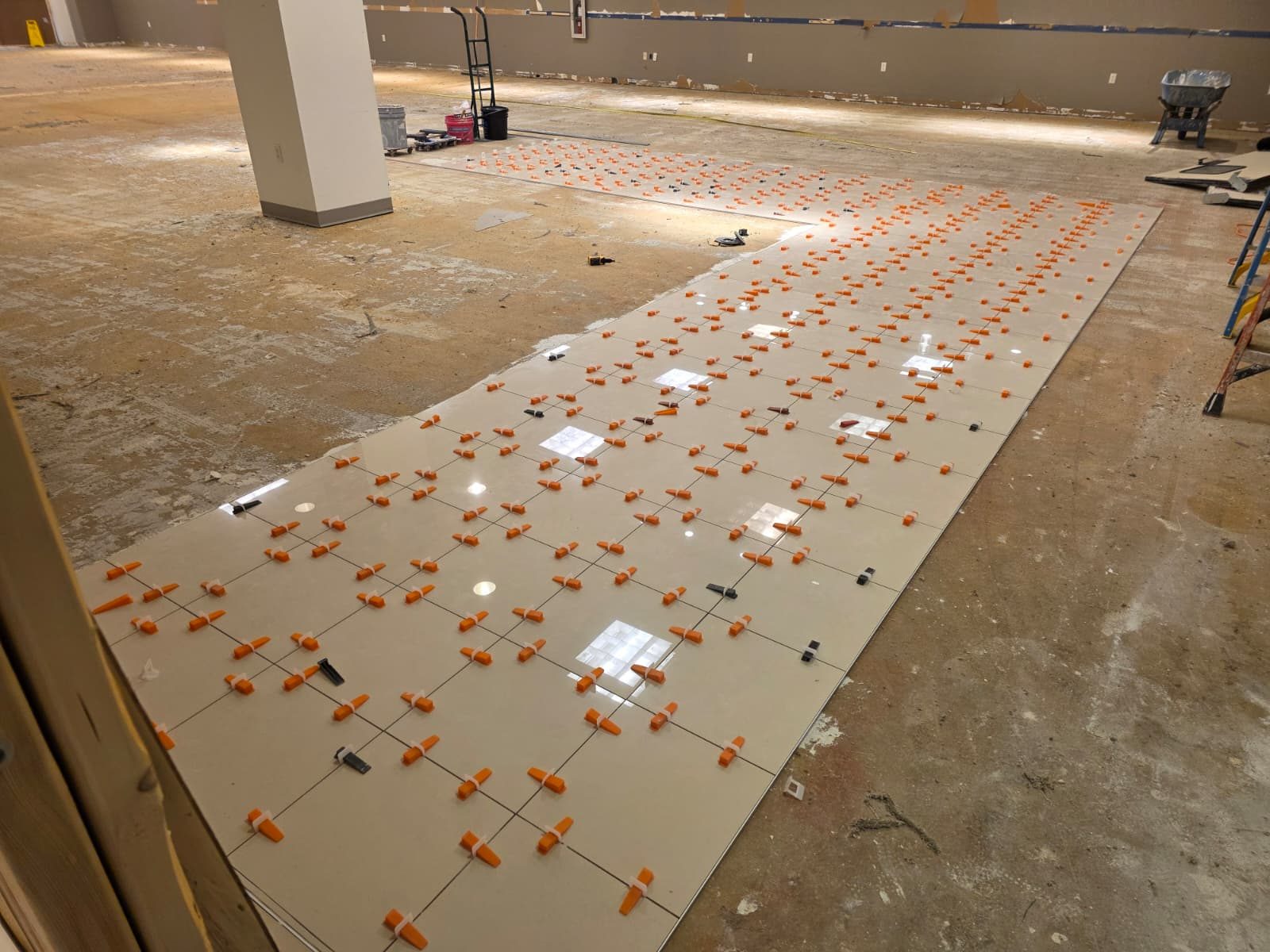 Polished porcelain aisle turning the corner around a column, leveling clips in place