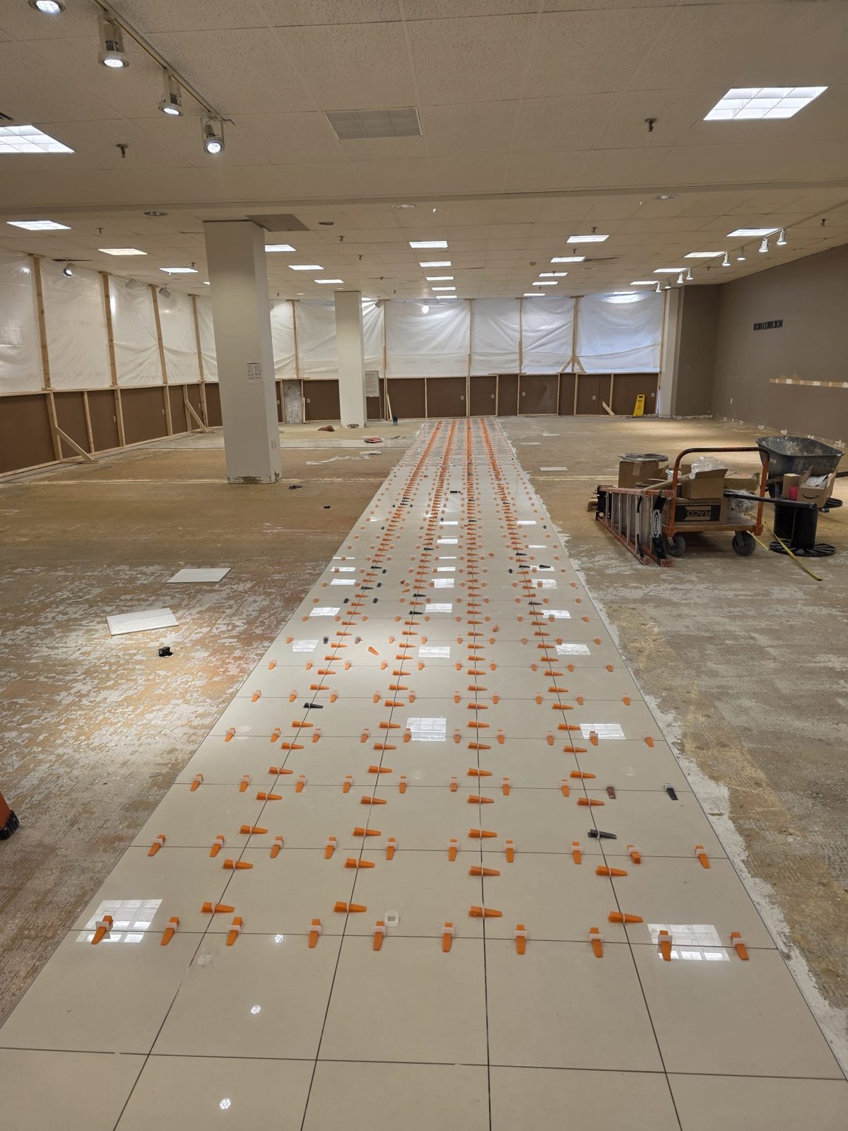 Sales floor demoed to slab, first run of polished porcelain aisle set with leveling clips