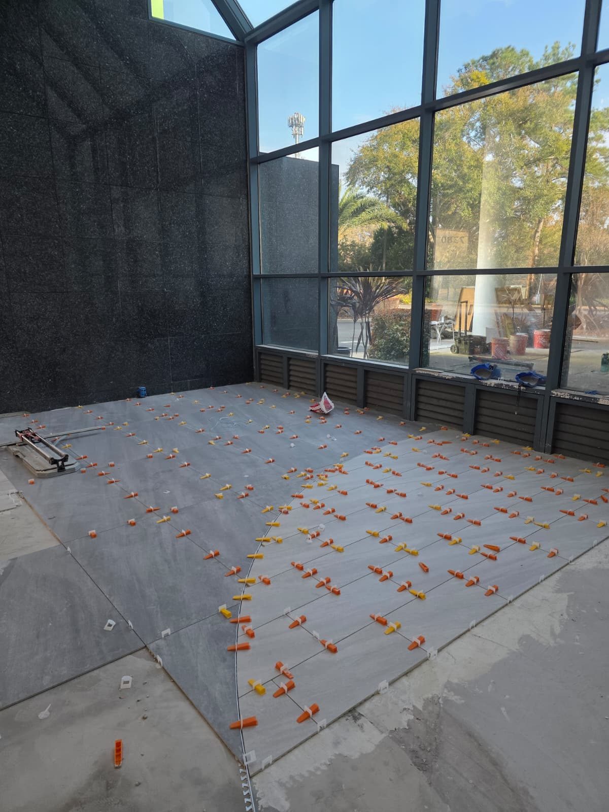 Large-format porcelain being set with leveling clips along the curved inlay line