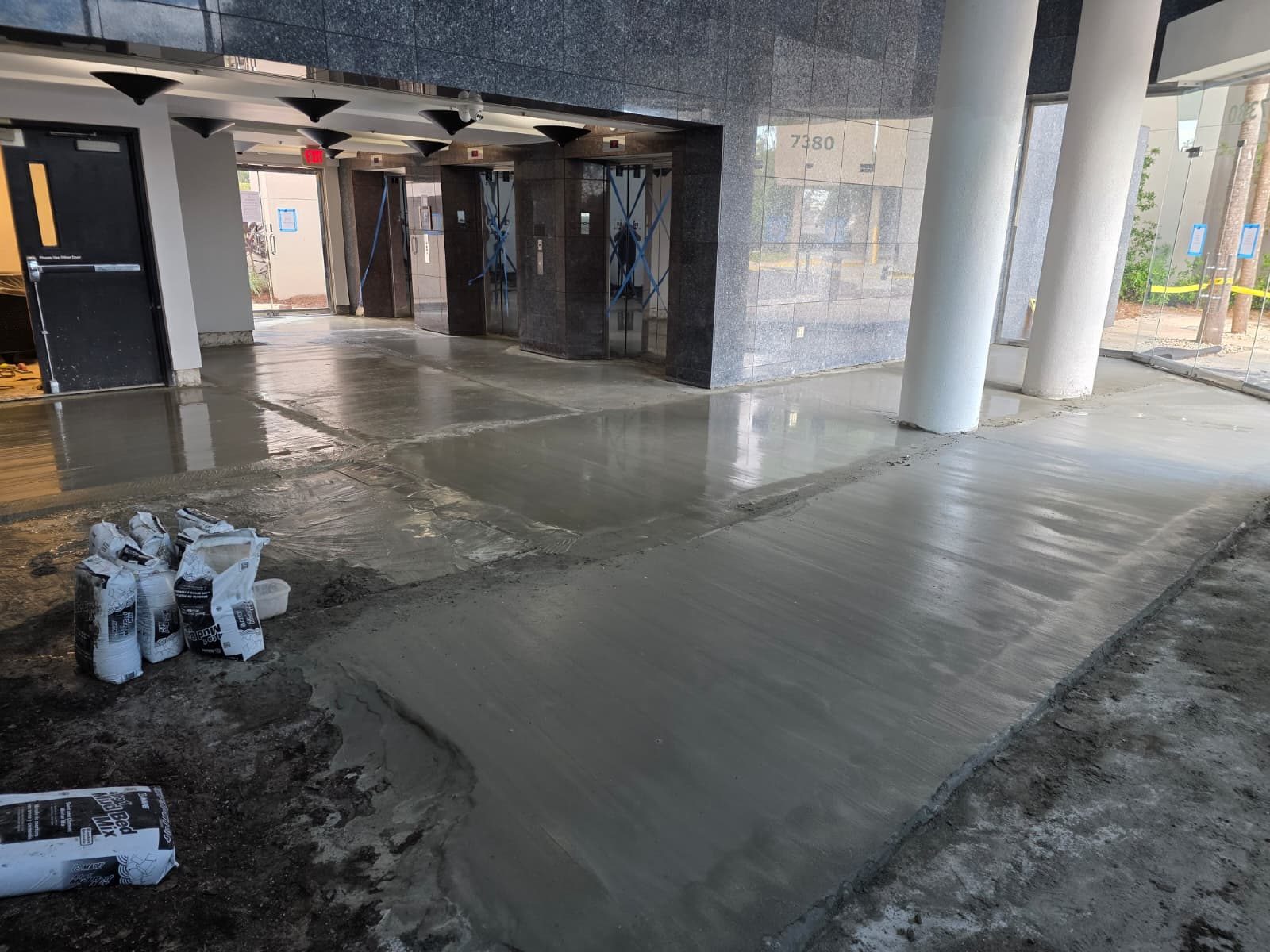 Lobby floor freshly self-leveled, elevators taped off, before tile